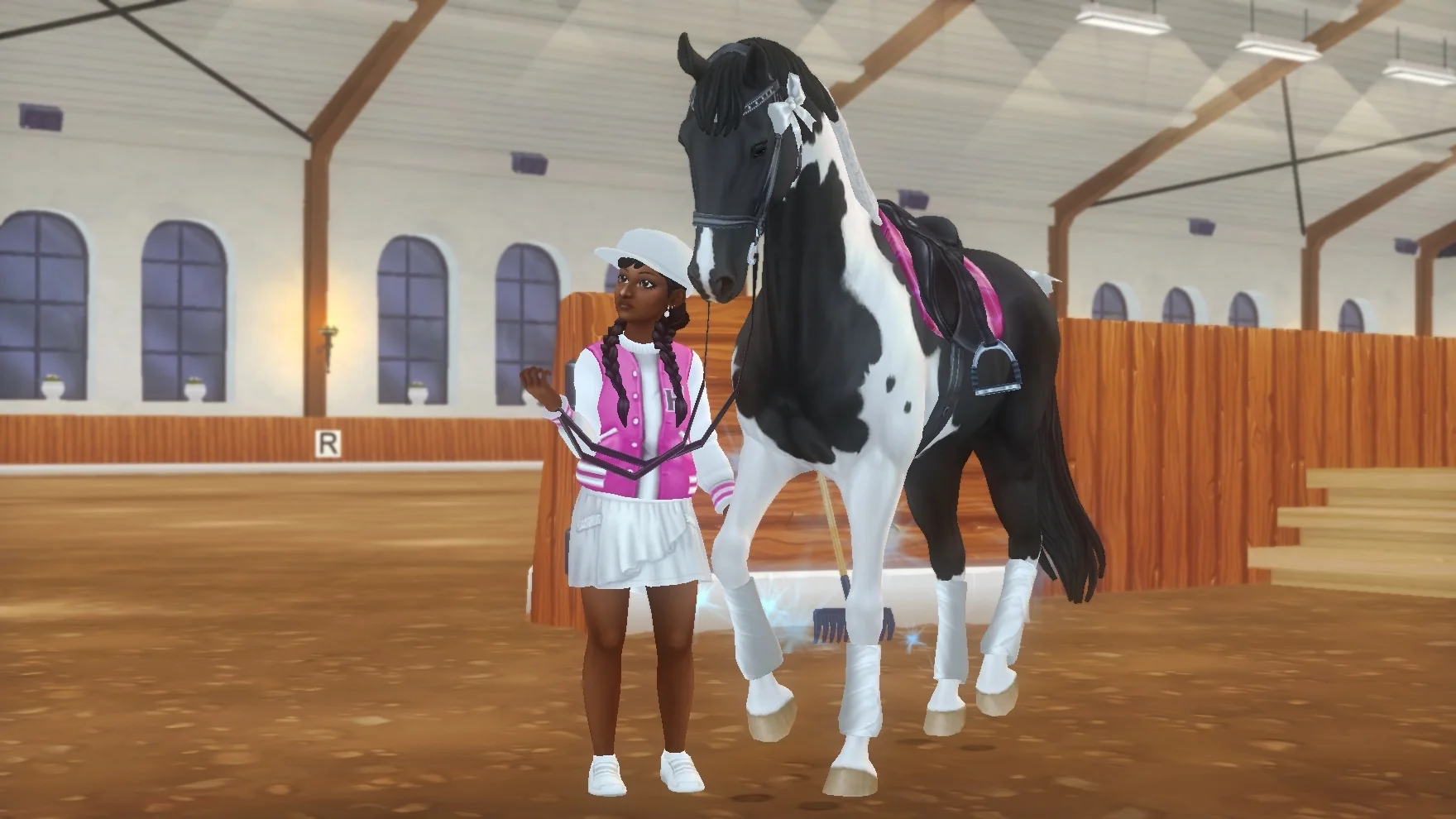 Pink Girls Squad rider standing beside a black-and-white horse in the arena